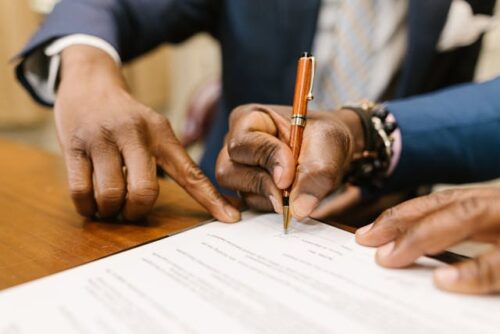 person pointing and man signing document