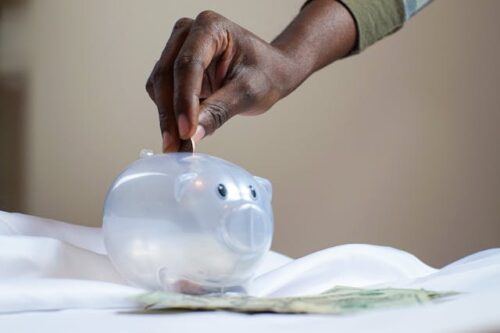 man putting coin into piggy bank